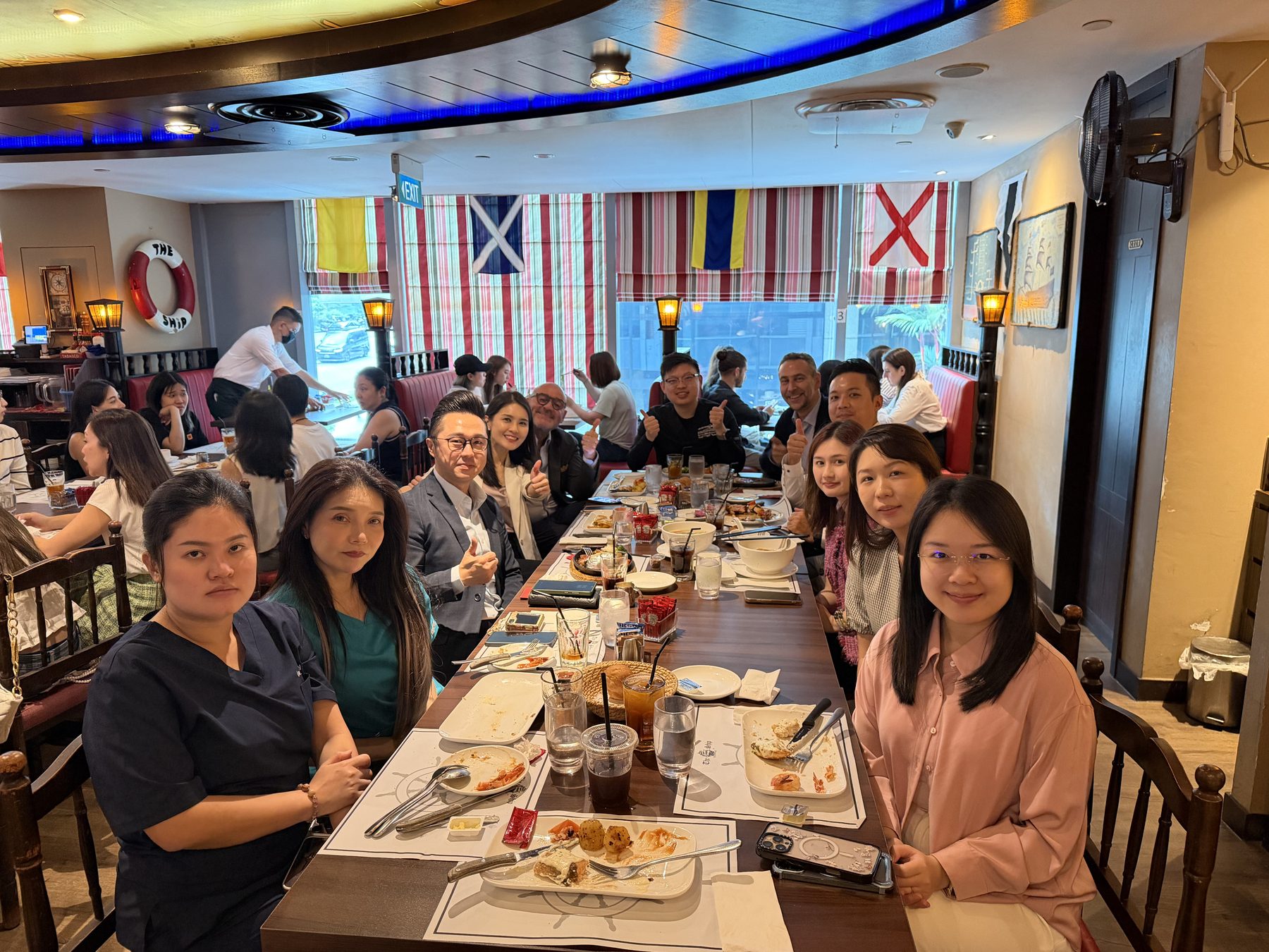 The clinic team and DEKA delegation over lunch during the July 2026 clinical exchange in Singapore
