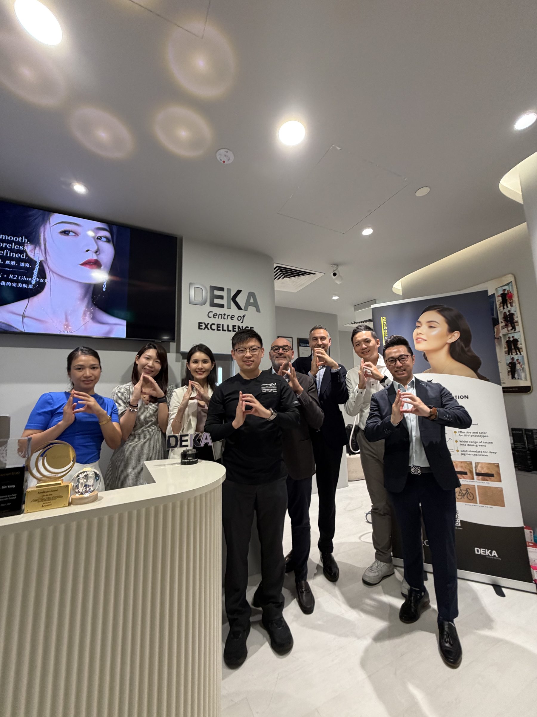 Dr Sin Yong and the clinic team with the visiting DEKA representatives at the Centre of Excellence signage