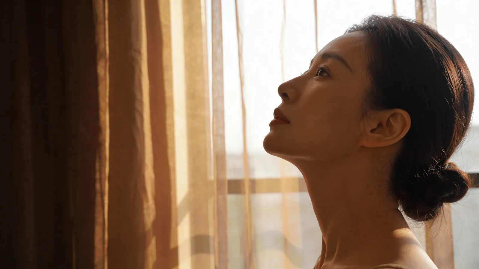 An East Asian woman in her 30s in side profile with chin lifted — illustrative image