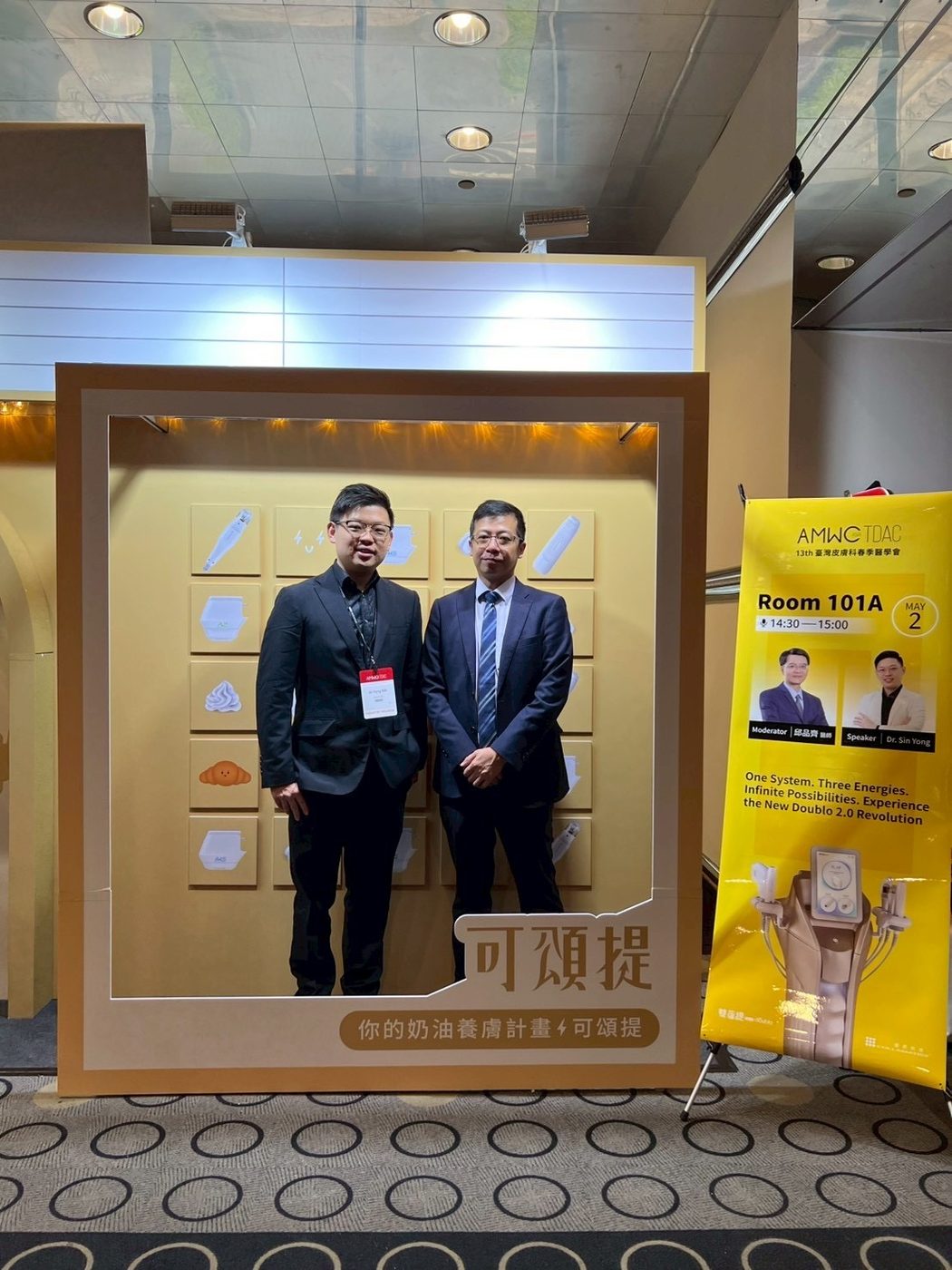 Dr Sin Yong with the Collamatrix host beside the AMWC TDAC session banner for the New Doublo 2.0, Room 101A