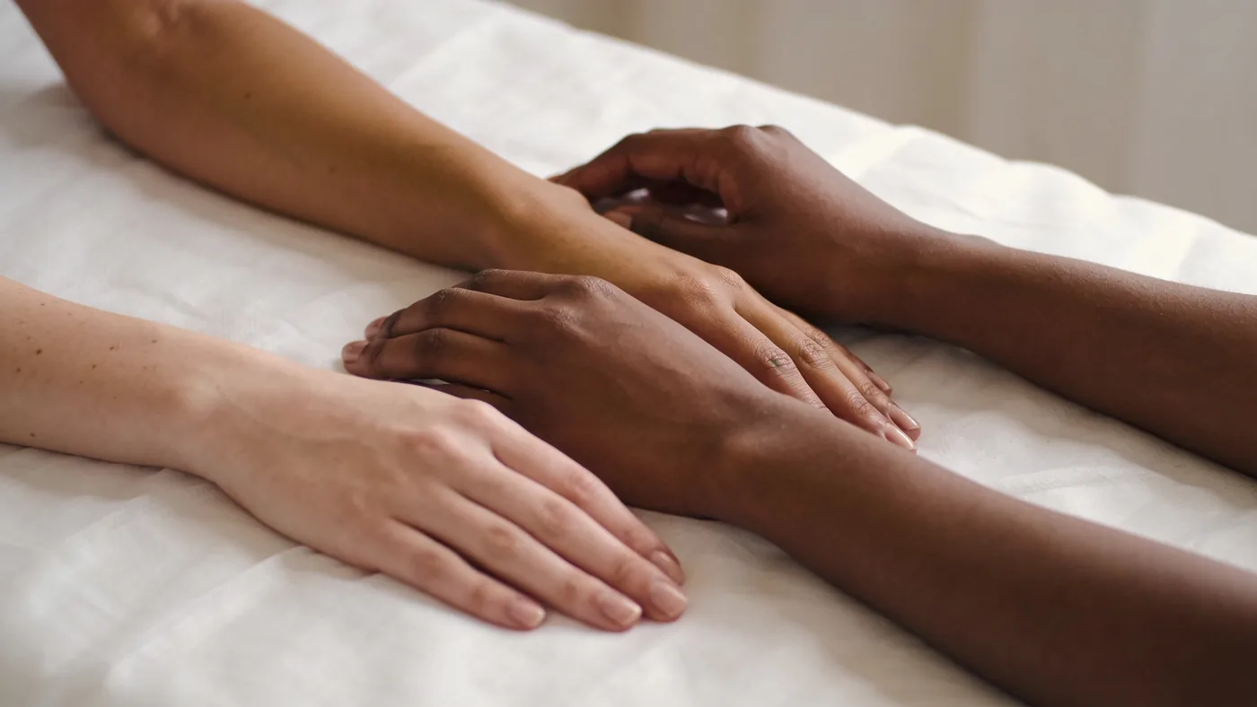 Three forearms of different skin tones resting side by side on white linen